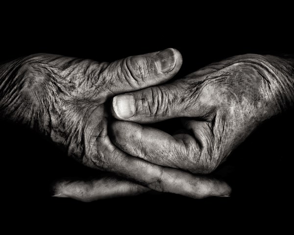 Two Wrinkled Hands against Black Background