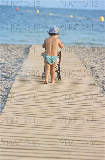 Rear View of Young Girl Pushing Stroller at Beach