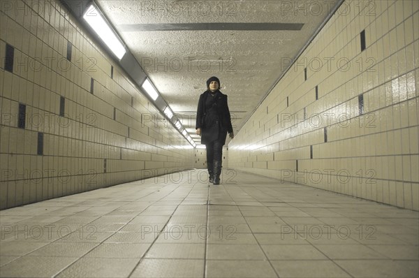 Young Adult Woman Walking through Underground Pedestrian Tunnel