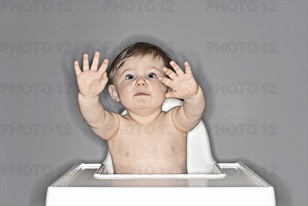 Baby Boy Sitting in Highchair and Waving