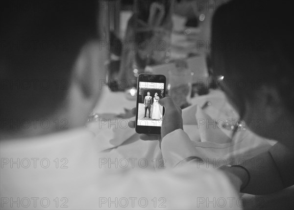 Two People looking at Picture of Wedding Couple on Smart Phone