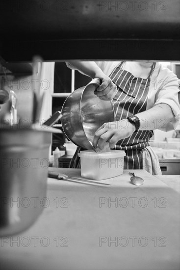 Chef putting Grated Cheese in Plastic Container