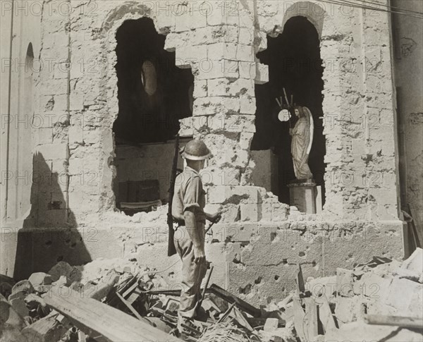 British Soldier standing in Rubble looking through Gaping Holes in Damaged Catholic Church