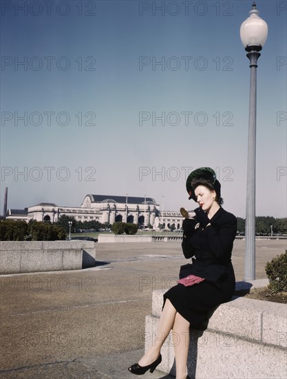 Woman putting on Lipstick in Park with Union Station in Background