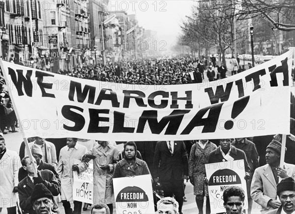 Marchers carrying banner "We March with Selma!" on street in Harlem, New York City, March 1965