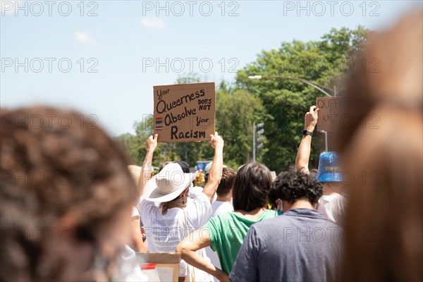 Protester holding up Your Queerness does not Absolve your Racism Sign during Protest, Brooklyn,