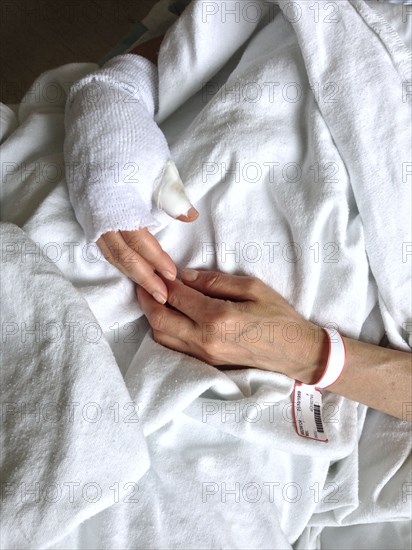 High Angle View of Woman with Injured Hand in Hospital Bed,,