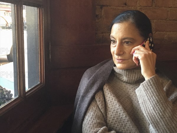 Mid-Adult Woman talking on Cell Phone in Restaurant,,