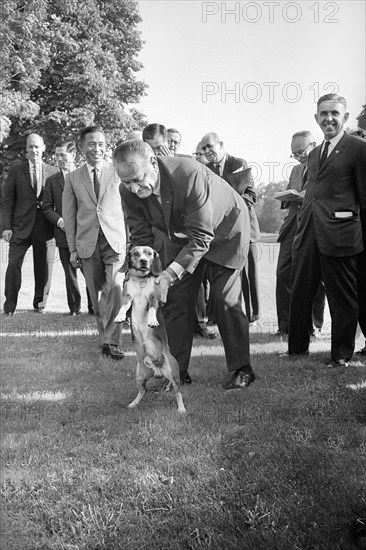 U.S. President Lyndon Johnson playing with his pet dog, South Korean President Park Chung-hee in background left