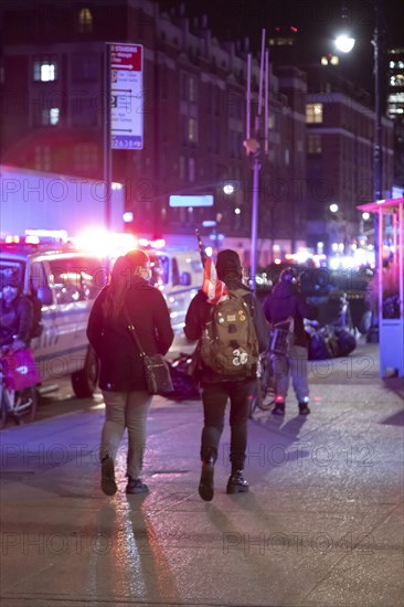 Pedestrians walking with American Flag against NYPD Van and Police Lights at Night, Greenwich Village