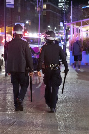 Rear View of Two Heavily Geared NYPD Officers walking with Helmets and Baton swinging, Greenwich Village