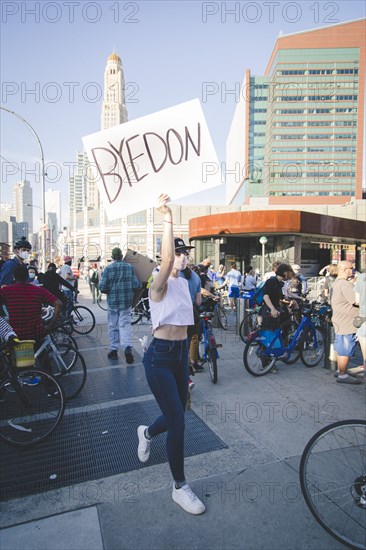 Woman walking in Crowd with "Byedon" Sign outside Barclays Center during Celebration of President-Elect Joe Biden, Brooklyn