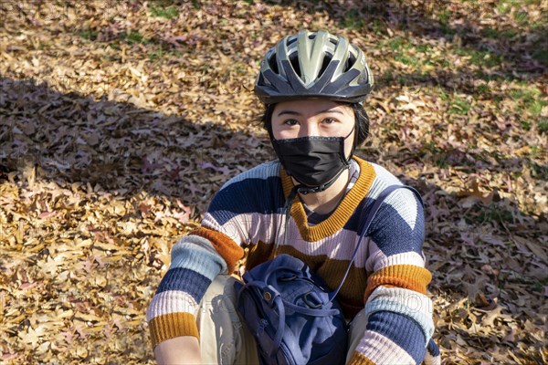 Teen Girl wearing Bicycle Helmet and Protective Mask, half-length seated Portrait