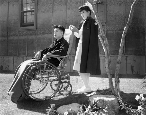 Nurse Aiko Hamaguchi standing behind a patient Tom Kano in Wheelchair