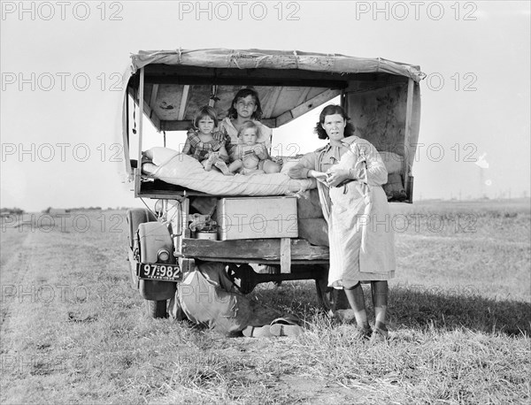 Portrait of Migrant Family while Father is repairing car tire