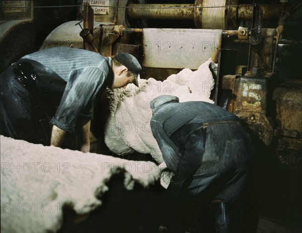 Workers removing synthetic rubber from rolling mills