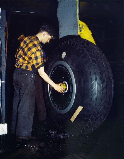 Worker inspecting landing wheel of Transport Plane