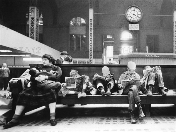 Woman and children seated on bench of train station concourse