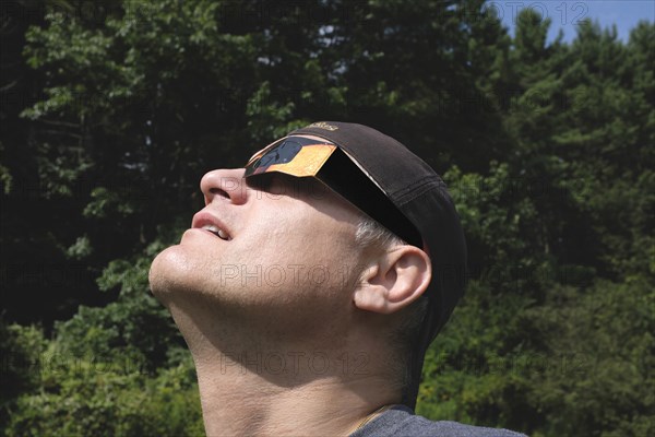 Mid-Adult Man wearing Eclipse Glasses while viewing Partial Solar Eclipse