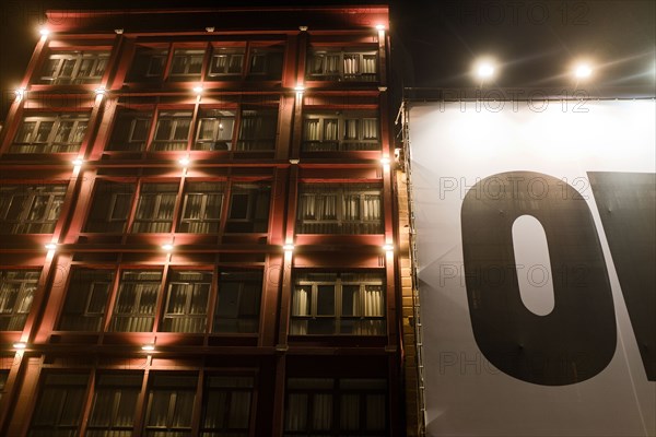 Illuminated Apartment Building with large canvas sign at Night