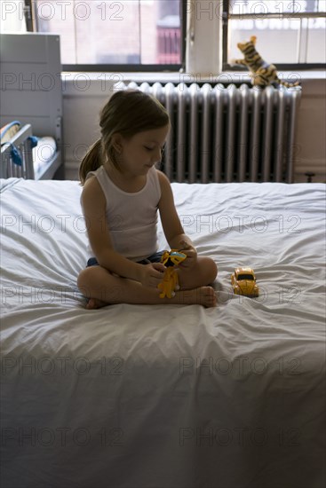 Young Boy sitting on Bed playing with Toys