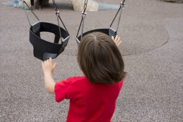 Rear View of Young Boy pushing Baby Swings