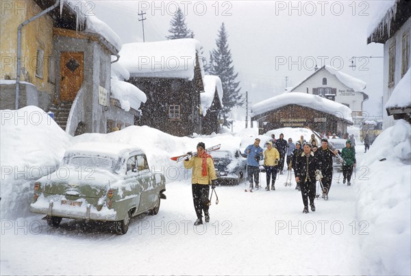 Group of Skiers walking through Village on Snowy Day