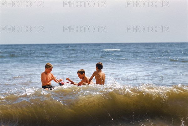 Three Boys playing in Ocean at Beach