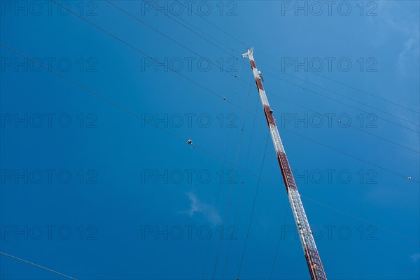 Low Angle View of Communications Tower with Guide Wires against Blue Sky