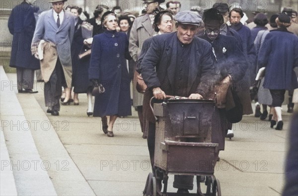 Man pushing Cart of Roasted Chestnuts on Sidewalk