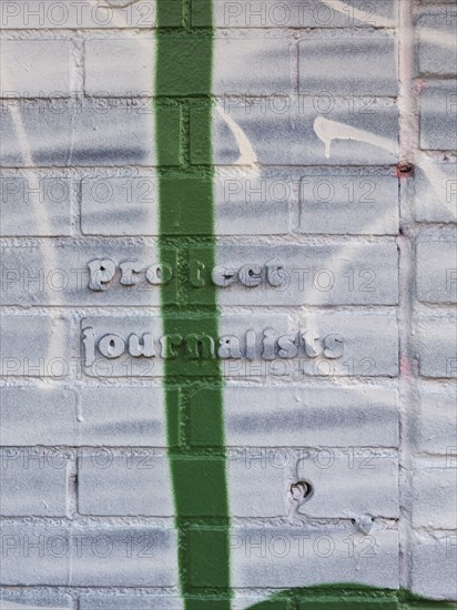 Protect Journalists quote on brick wall covered in paint and graffiti