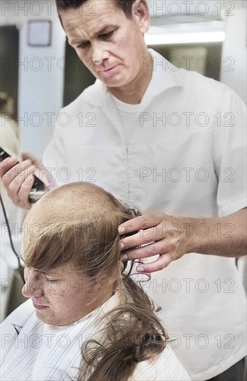 Young U.S. soldier who had just been drafted into U.S. Army getting head shaved by barber