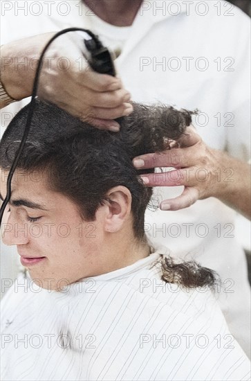 Young U.S. soldier who had just been drafted into U.S. Army getting head shaved by barber