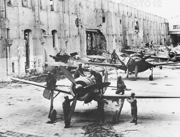 U.S. Army Quartermaster troops inspecting found Focke-Wulf fighter planes grounded either by rubble or lack of gasoline