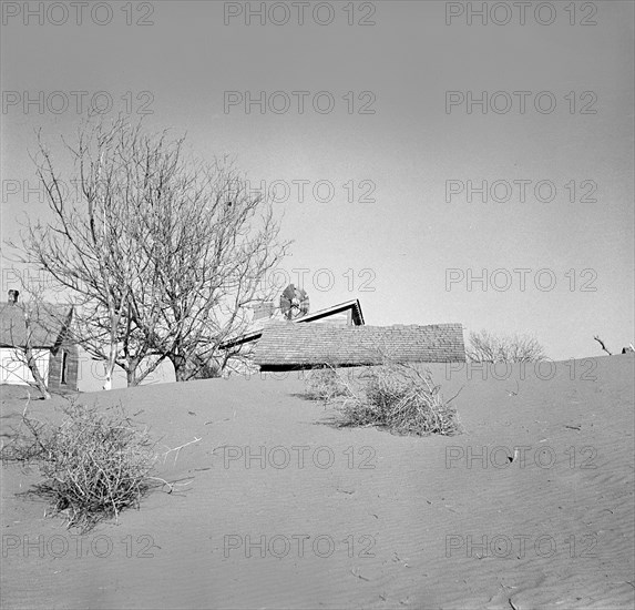 Drifts of top soil threatening to cover farmer's house