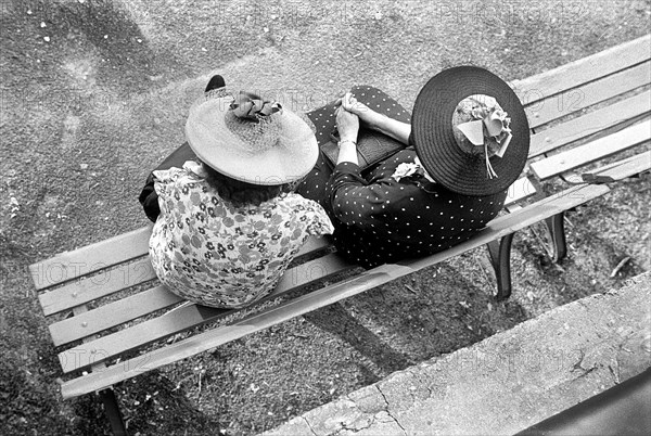 Women wearing print dresses and large straw hats