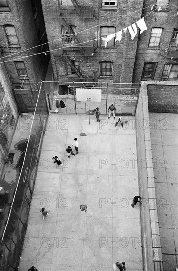 High angle view of Puerto Rican children playing basketball in courtyard surrounded by  buildings