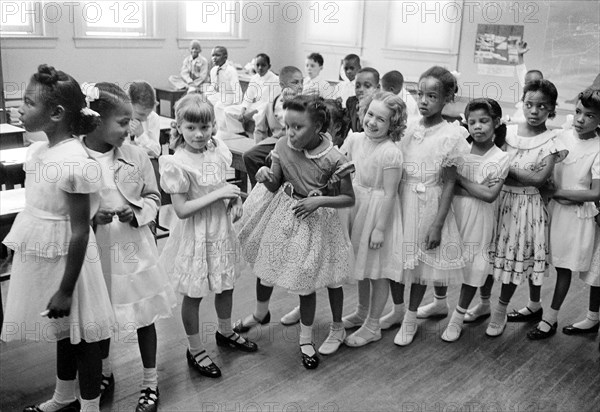 Racially integrated classroom of young girls in a row with boys sitting behind them