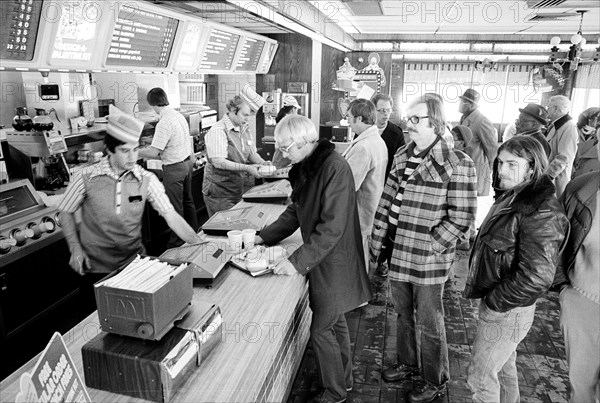 Employees behind  counter serving  lines of customers at McDonald's fast food restaurant