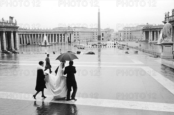 Bride and others crossing St. Peter's Square in the rain