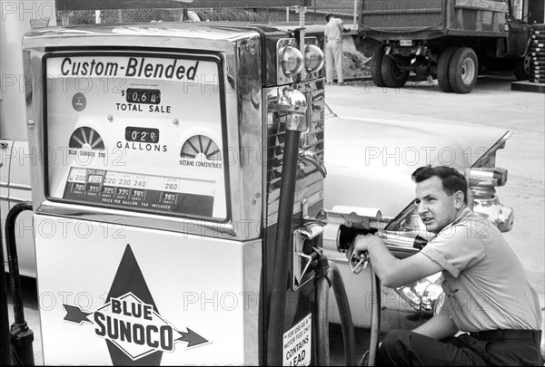 Gas station attendant filling car tank with custom blended gas at Sunoco gas station