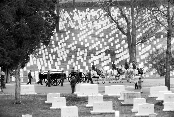 Flag-draped casket carried by horse-drawn caisson during a funeral