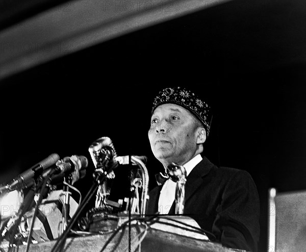 Elijah Muhammad standing behind microphones at podium