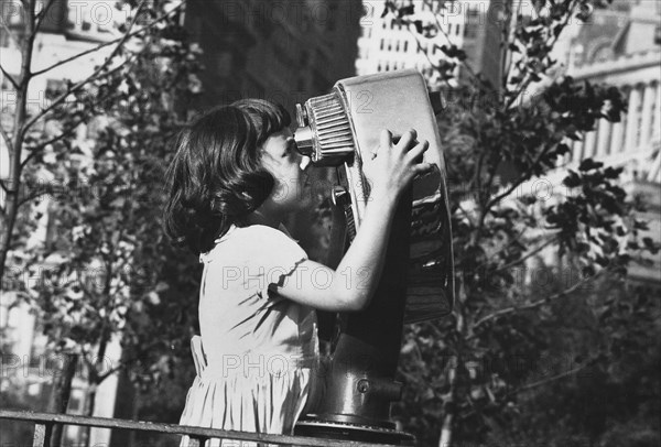 Young girl looking through coin-operated observation binoculars