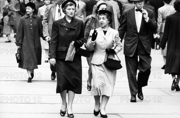 Two women talking while walking on sidewalk