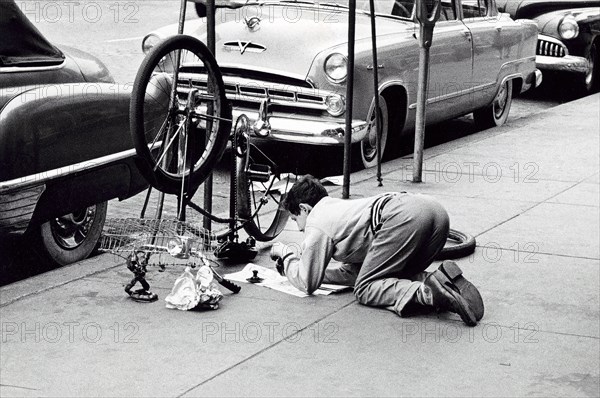 Man fixing bicycle on sidewalk