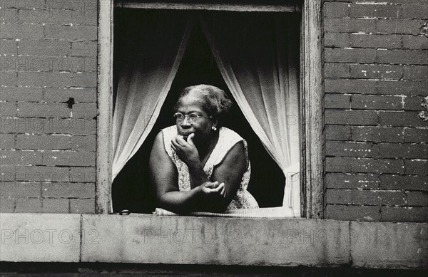 Woman looking out open apartment window