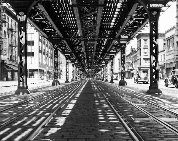 Street scene showing streetcar tracks and underside of elevated railway tracks