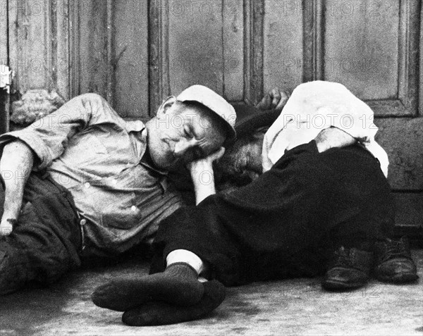 Two men lying down on sidewalk