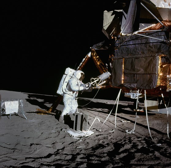 American astronaut Alan L. Bean using fuel transfer tool to remove fuel element from fuel cask mounted on lunar module during Apollo 12 extravehicular activity